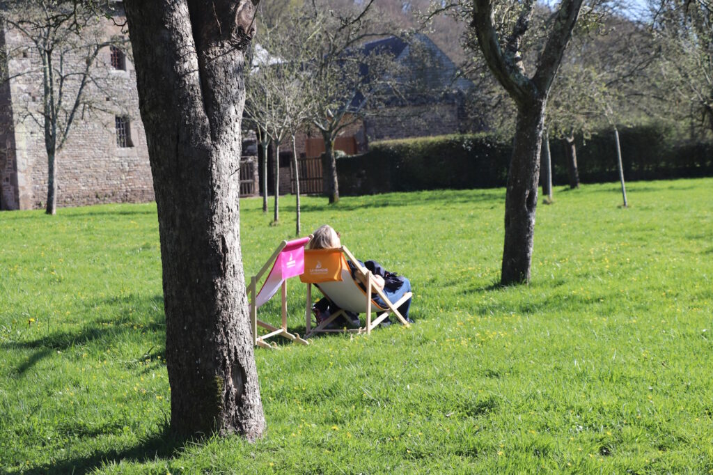 Une visiteuse profite du soleil sur un transat devant l'abbaye