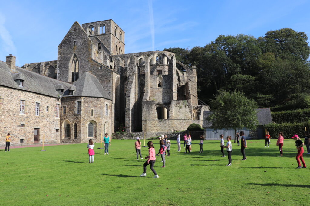 Un groupe scolaire pratique un atelier chorégraphique devant le chevet de l'église abbatiale de l'abbaye de Hambye