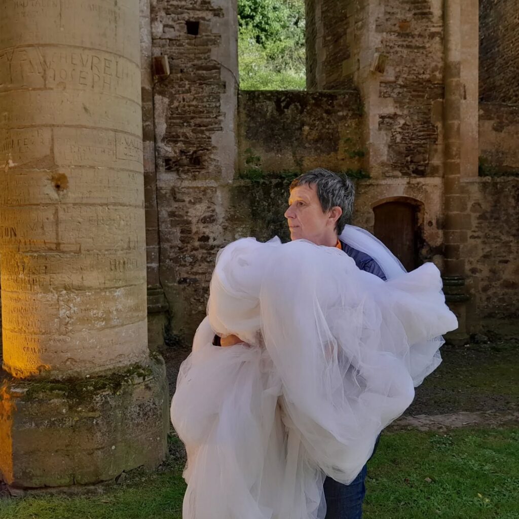 La chorégraphe et performeuse Sophie Quénon installant le décor en tissus blanc lors des repérages sur site