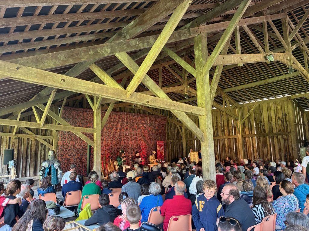 Concert sous la grange de l'abbaye. de nombreuses personnes écoutent les musiciens sur la scène.