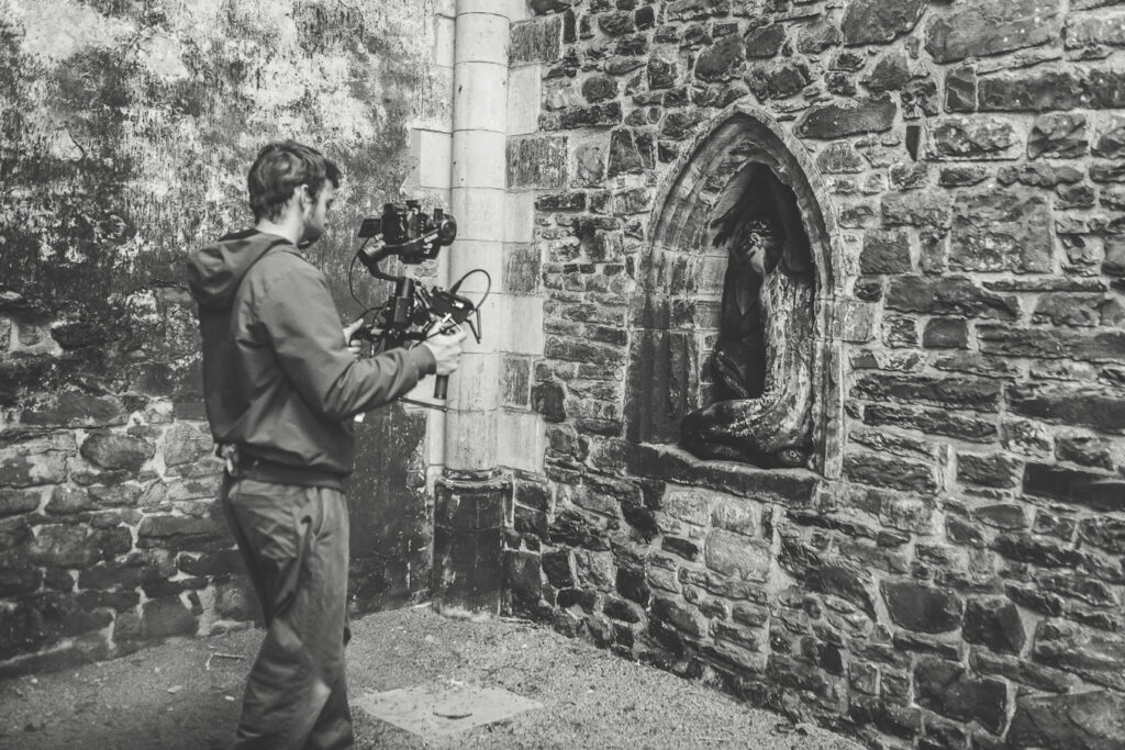 Un cineaste filme une danseuse dans une alcôve. L'image est en noir et blanc.