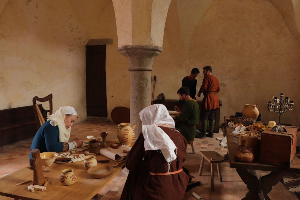 Deux femmes habillées en costumes médiévaux réalisent de la calligraphie dans le scriptorium.