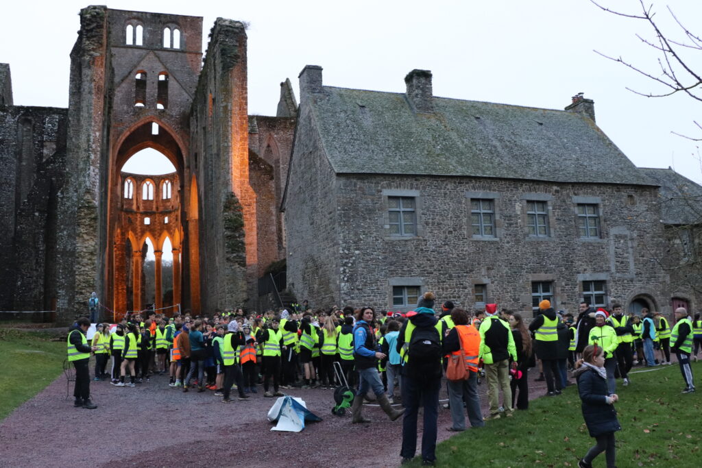 Avant le départ du trail, les collégiens sont rassemblés devant l'église abbatiale. Il fait encore jour.