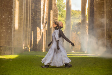 Deux danseurs en costume blanc se tiennent au centre de l'église abbatiale