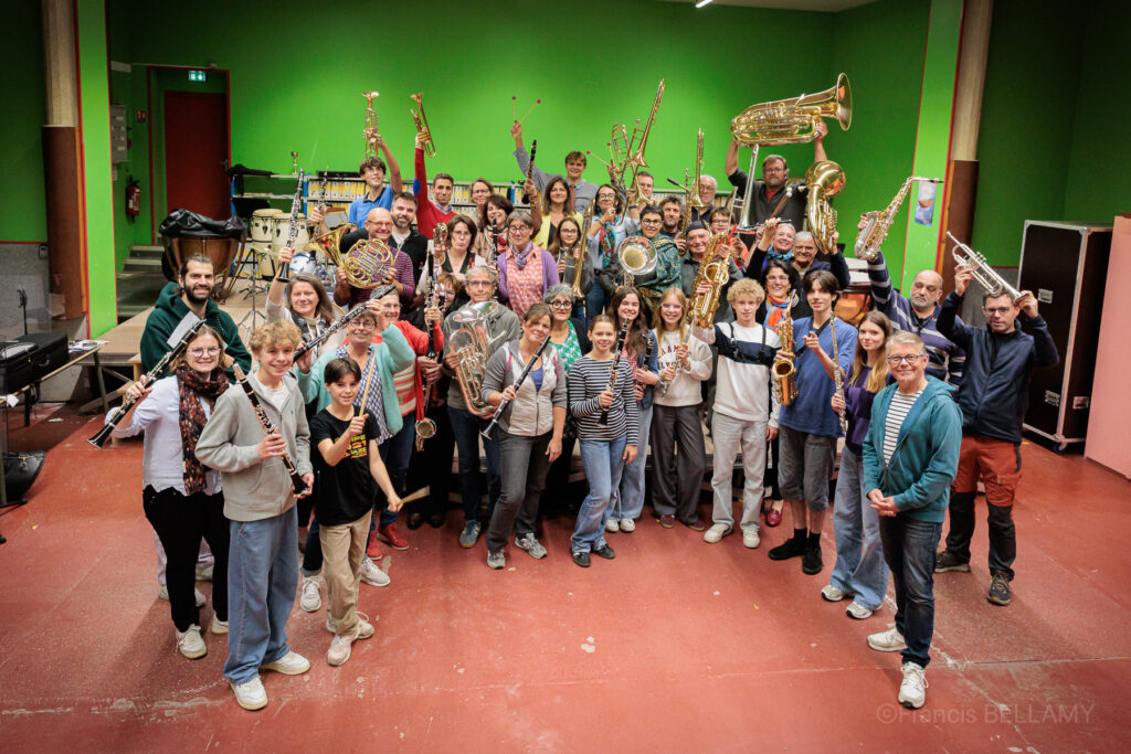 Les 60 musiciens de l'orchestre d'Harmonie brandissant leurs instruments dans la salle de répétition